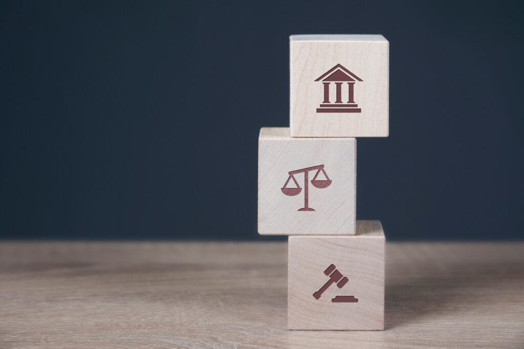 Stacked blocks with icons of a columned building, scales, and a gavel.