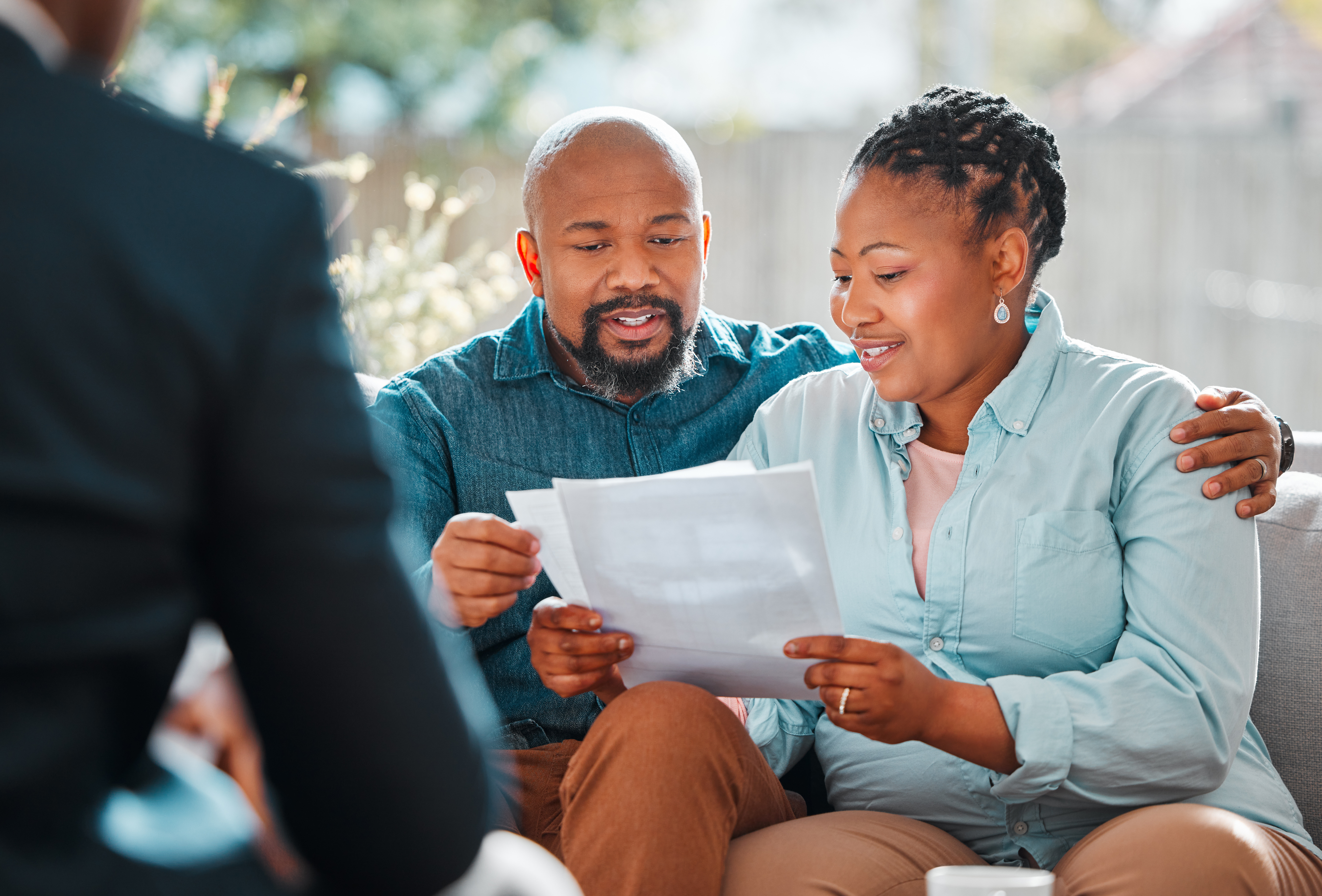 A seated man and woman smile as they examine a document together.